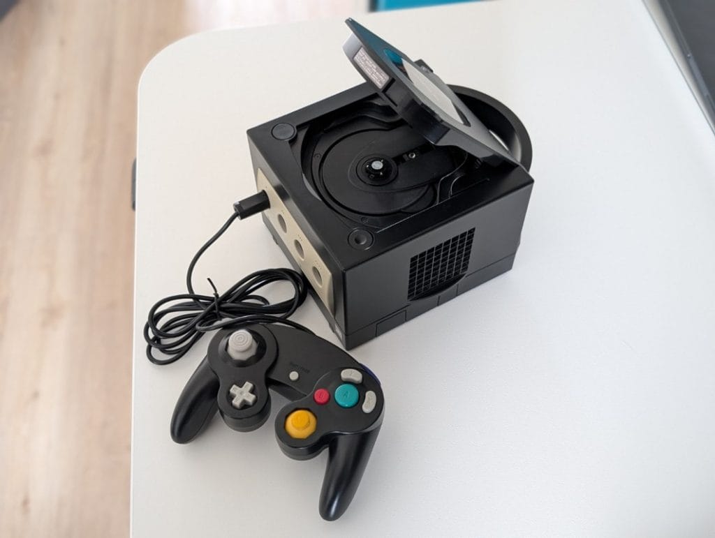 Nintendo GameCube cu capacul deschis și controller original conectat, detaliu tehnic