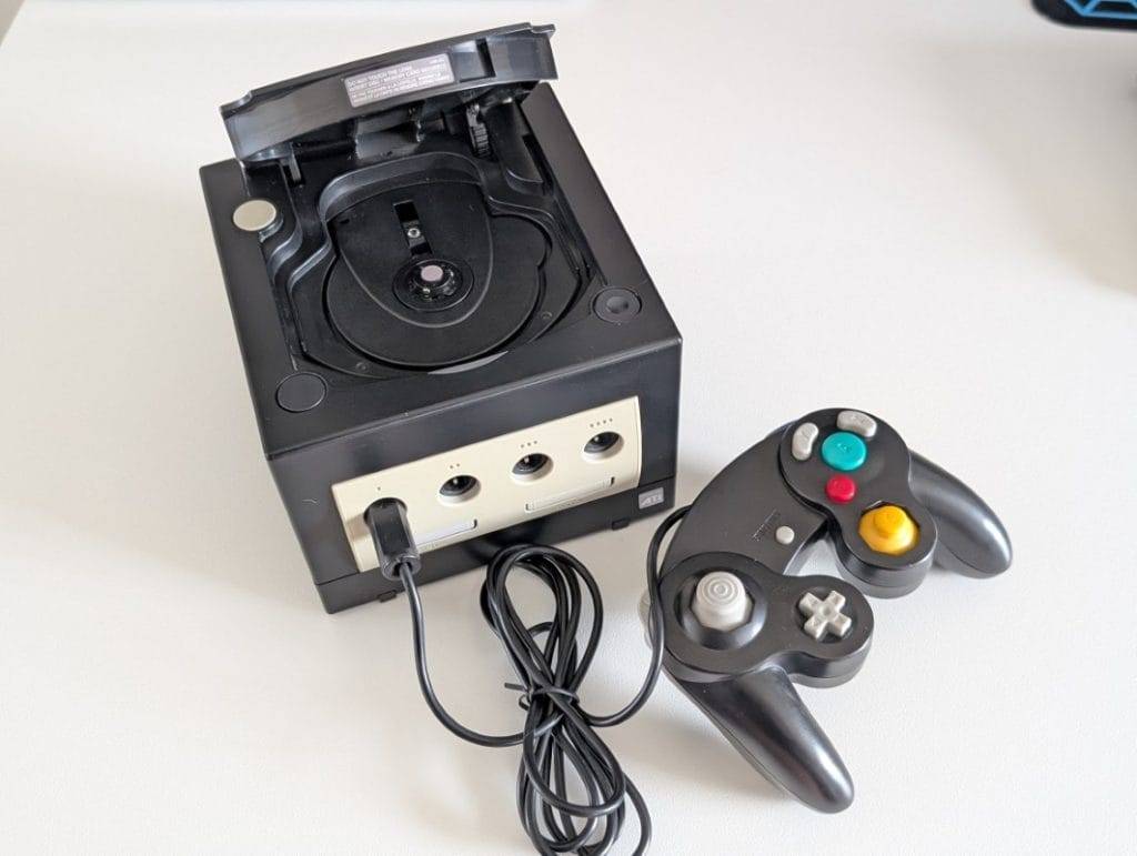 Nintendo GameCube cu controller original conectat, fotografiat într-un setup de gaming retro